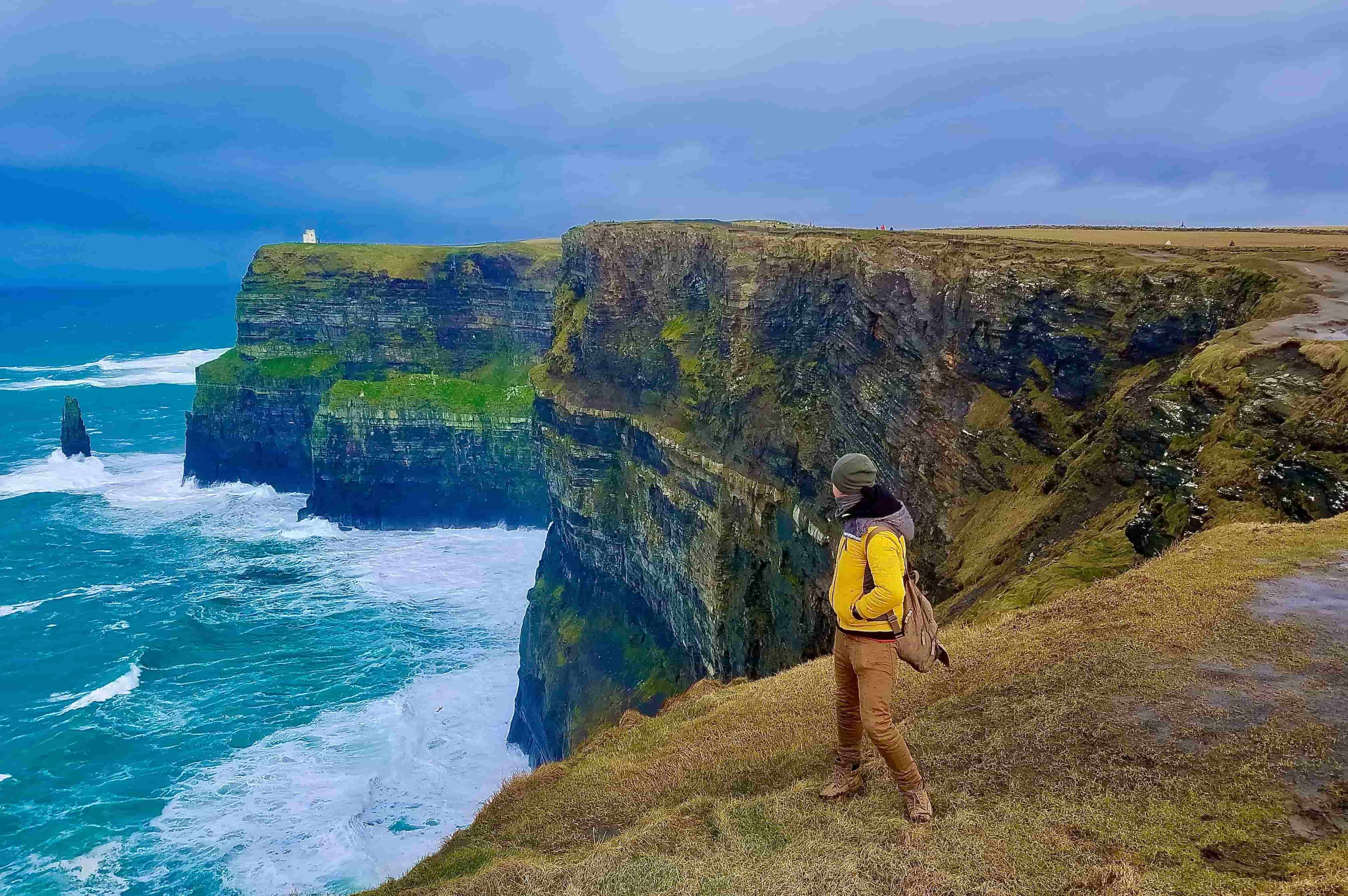 person on cultural excursion stands at edge of Cliffs of Moher in Ireland