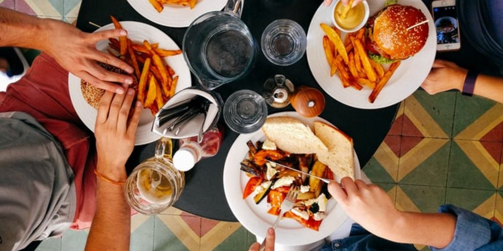 three people at table with food and drinks