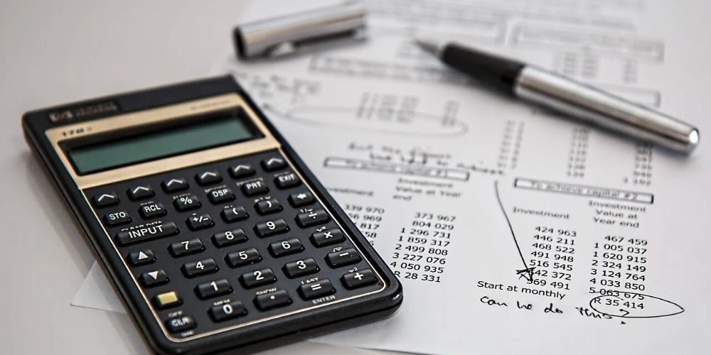 calculator on table with pen and paper showing figures